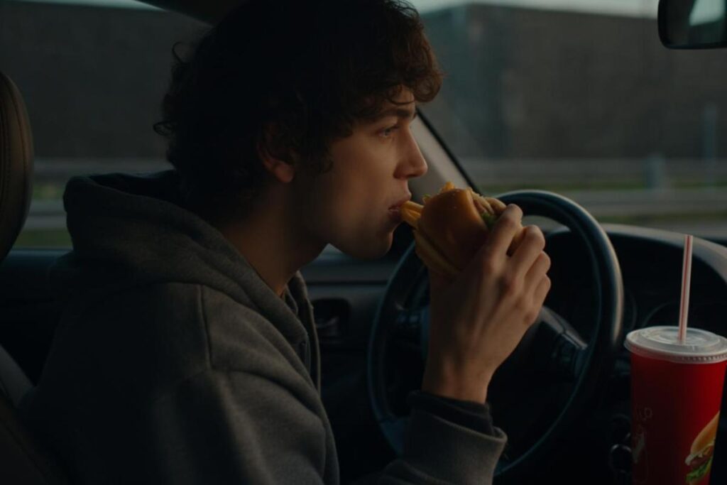 Uomo mangia un panino al volante della propria automobile