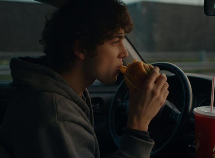 Uomo mangia un panino al volante della propria automobile